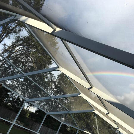 A screened roof has trees and a rainbow in the background
