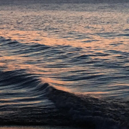 A picture of waves at sunset, they are blue and yellow-tinted